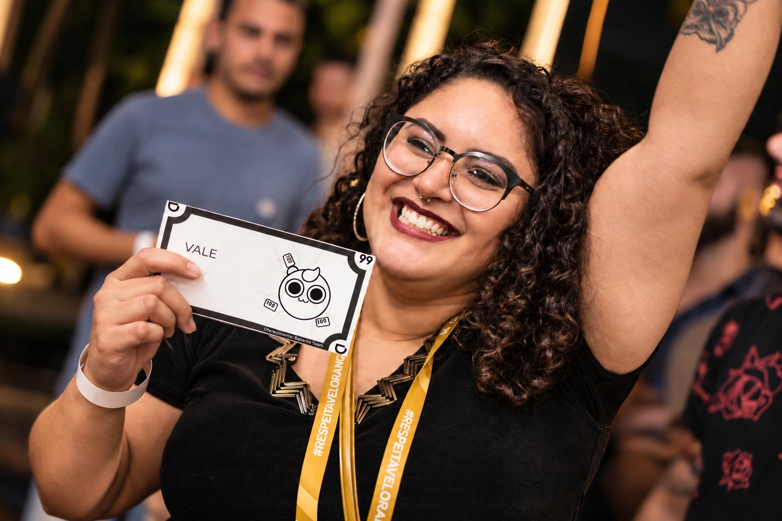 Participante sorrindo com um vale da 99 e o braço erguido durante uma celebração de reconhecimento